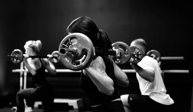 Small group lifting barbells together in a coached session