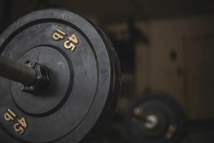 Worn bumper plates loaded on a bar in a garage-style gym
