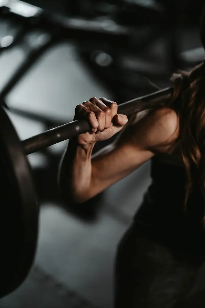 Lifter's hand gripping a barbell across the upper back before a squat