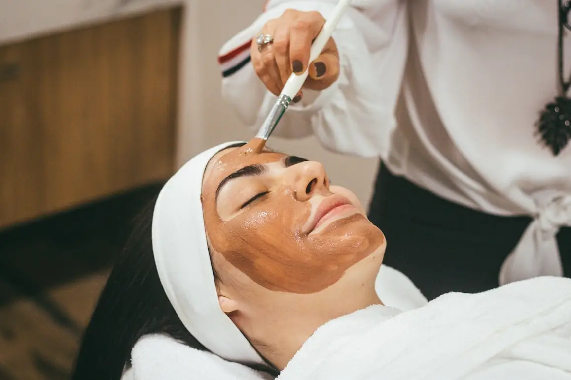 Provider applying a treatment mask to a client resting in a treatment chair