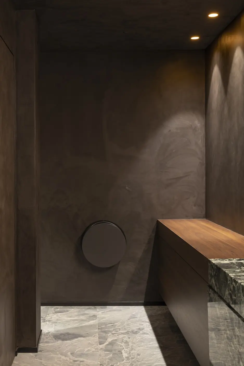 Quiet corridor with warm plaster walls, a wood bench and marble flooring