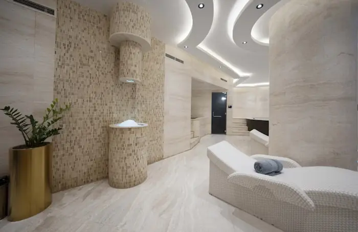 Treatment room in cream stone with a single bed and folded towel