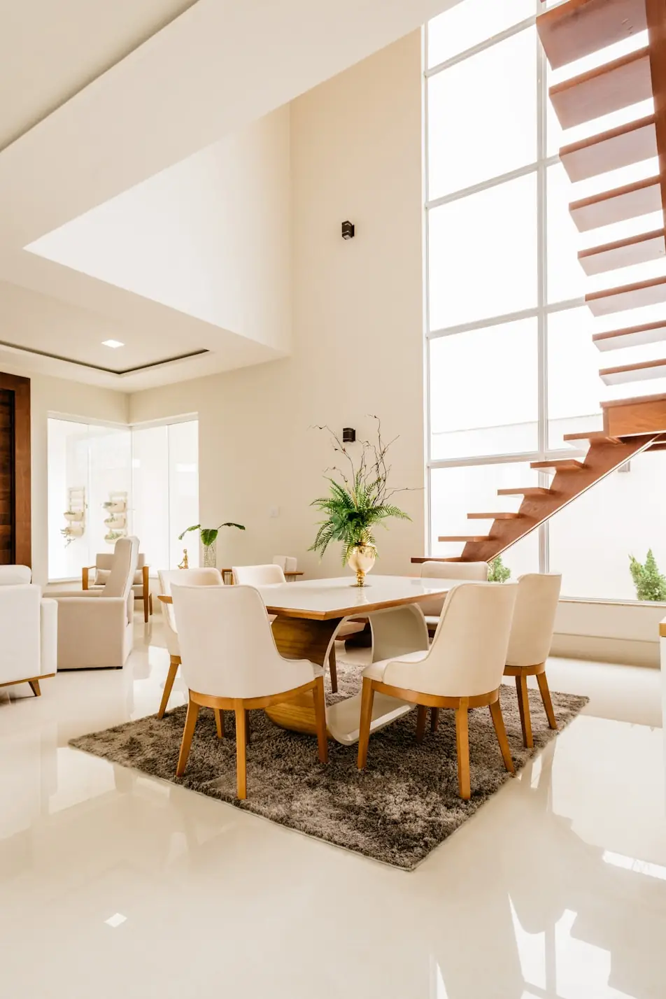 Double-height dining room with floating staircase and full-height glazing