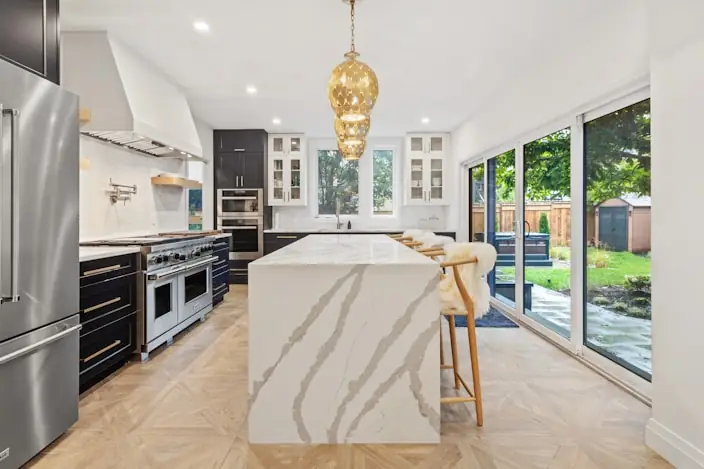 Kitchen with veined marble island and brass pendants