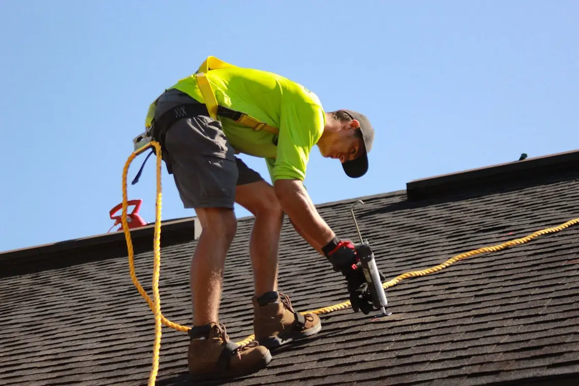 Roofer fastening architectural shingles on a residential roof