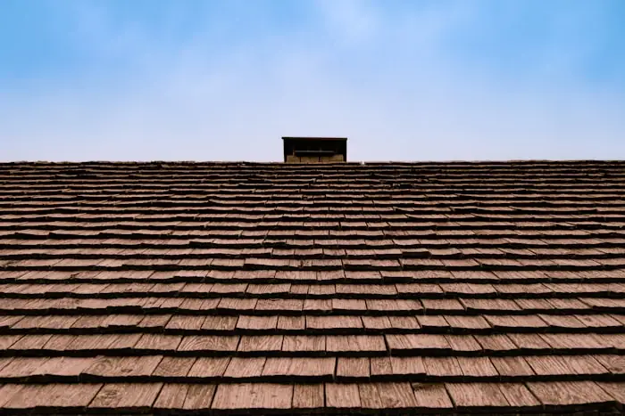 Close view up the slope of a shingled roof against blue sky